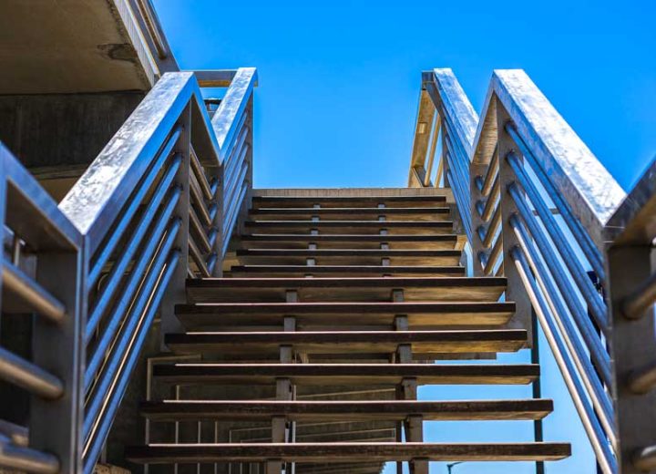 A closeup of a metal staircase of a building under the sunlight and a blue sky